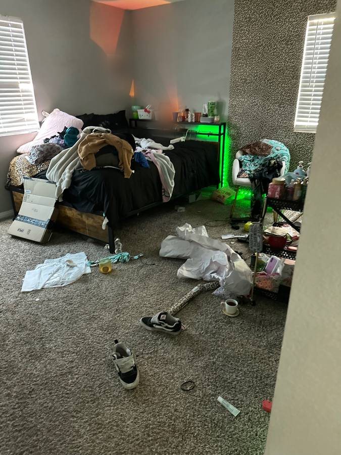 Messy bedroom before cleaning, with clothes, boxes and trash on the floor