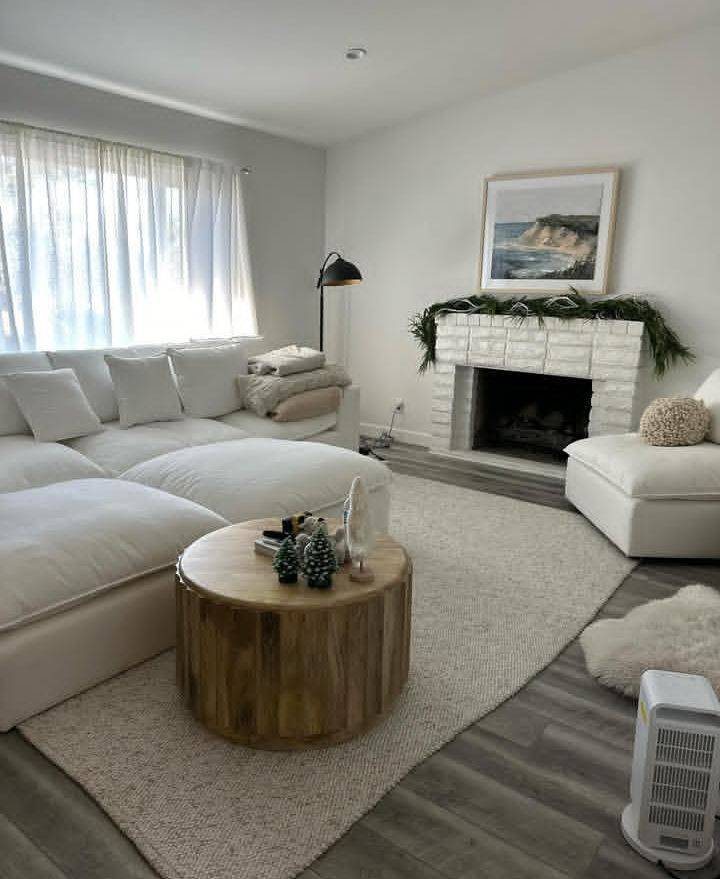 Bright living room with a white sectional and fireplace after a deep clean