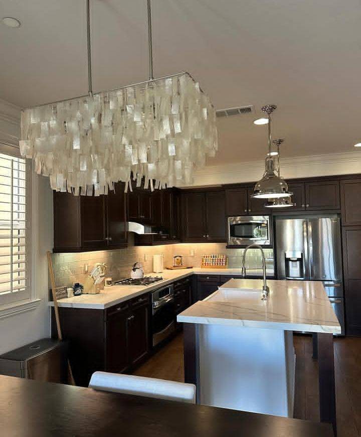 Kitchen with dark cabinets, marble island and capiz chandelier
