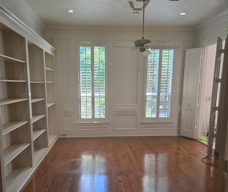 Empty study with built-in shelves and polished hardwood floors